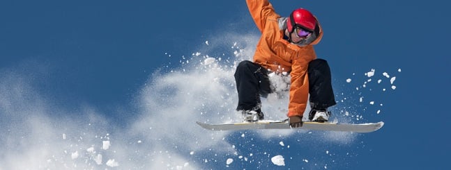 Young man suspended in mid-air making snowboard jump.