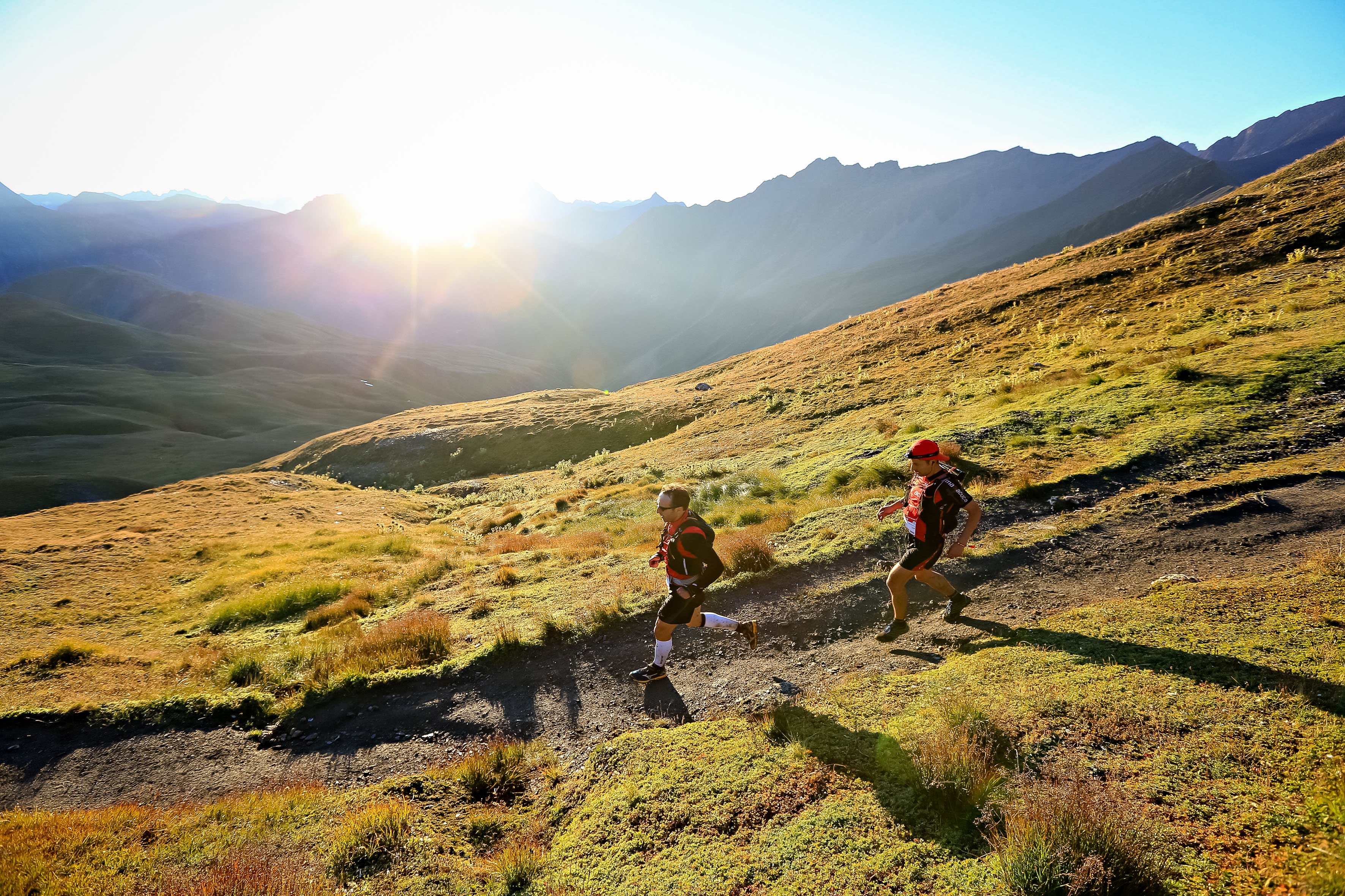 Trail runners in front of sun in the mountains